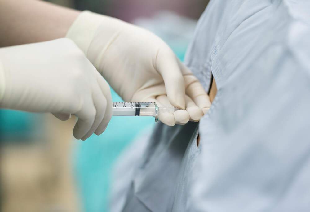A doctor is administering an injection with steroids