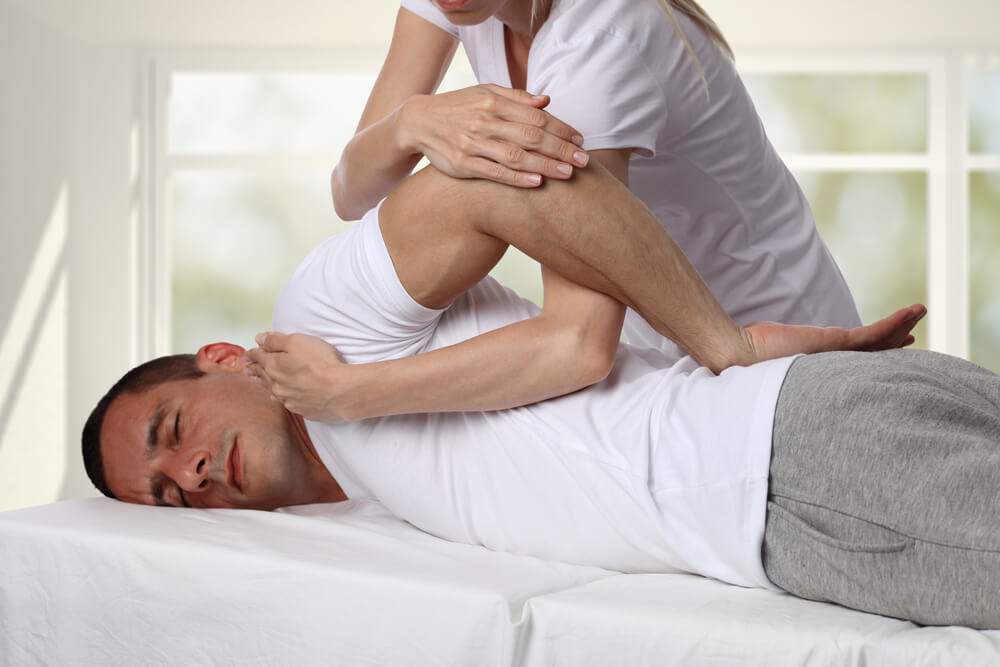 A physiotherapist is giving a massage to relieve back pain