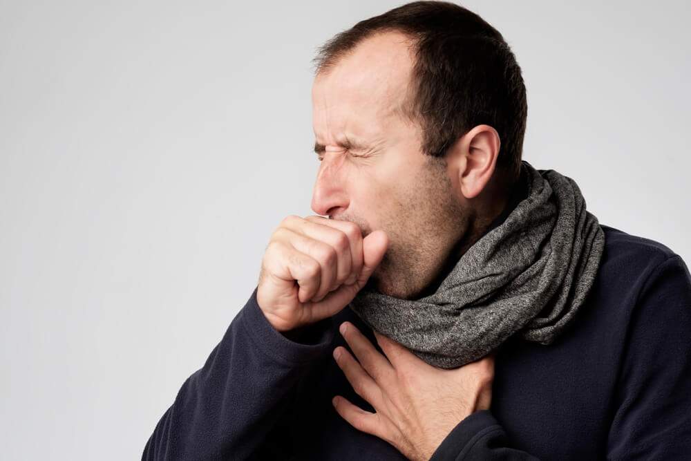 A man is coughing, which is one of his pneumonia symptoms